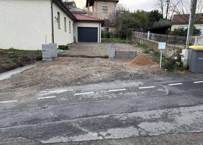 Entrée de maison avec fondations et piliers en parpaings bruts avant la pose de clôture